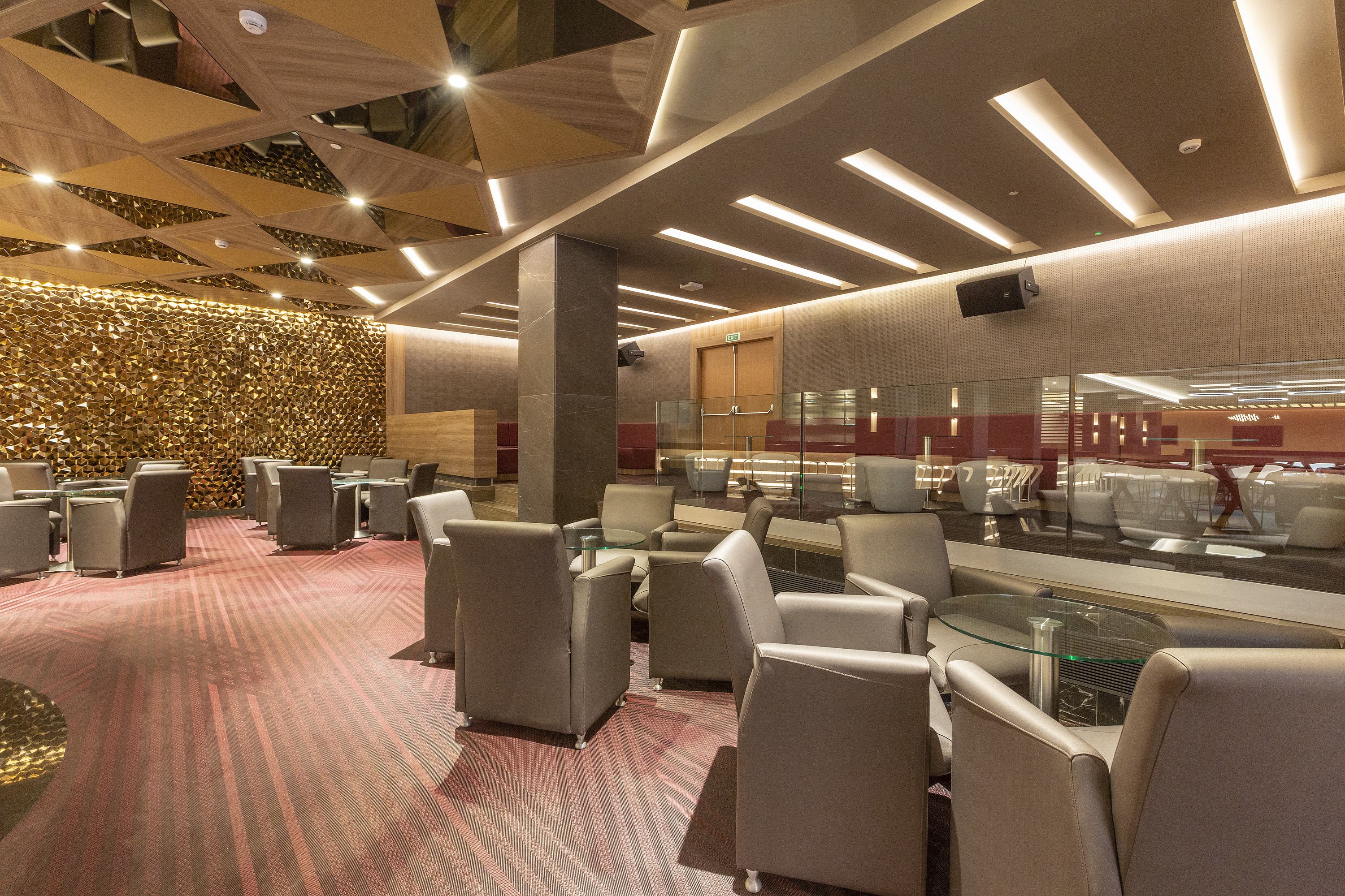 A modern lounge area with seating arrangements and a patterned wall.