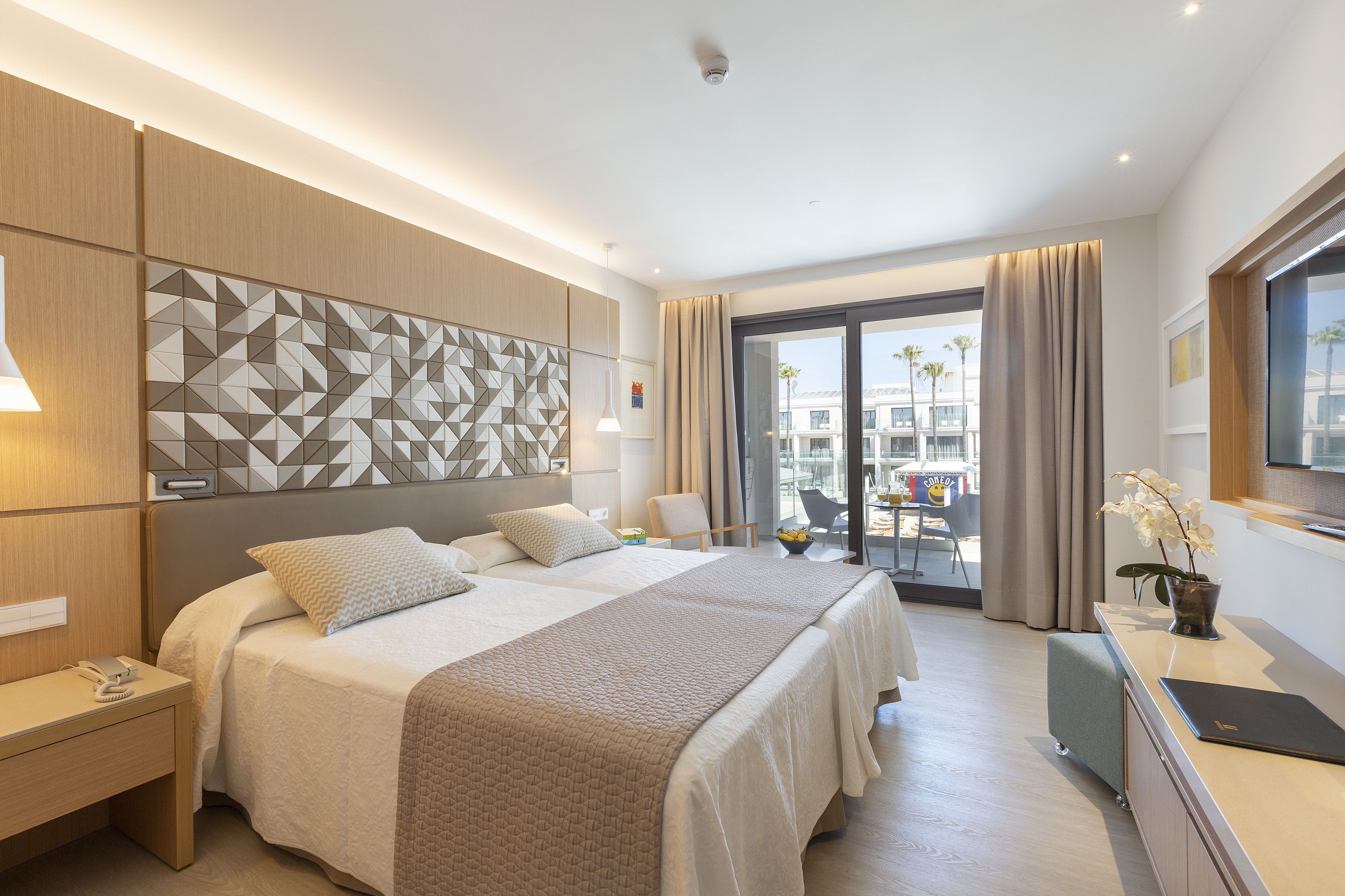 A modern hotel room with a large bed, a desk, and a view of the city.