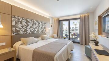A modern hotel room with a large bed, a desk, and a view of the city.