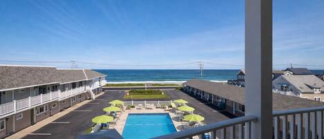 A motel with a pool, outdoor seating, and ocean views.