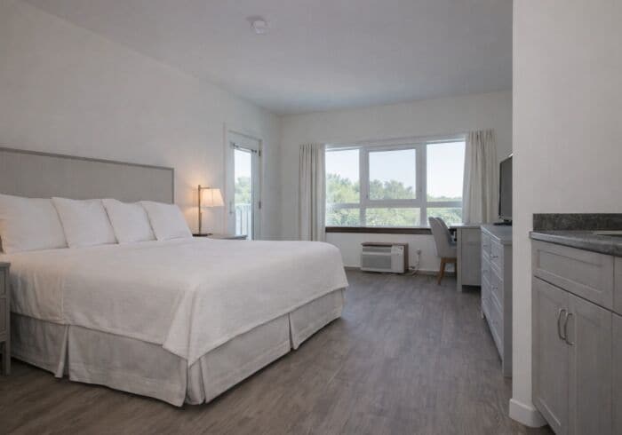 Ein Hotelzimmer mit einem großen Bett, einem Schreibtisch, einem Stuhl und einem Fernseher.