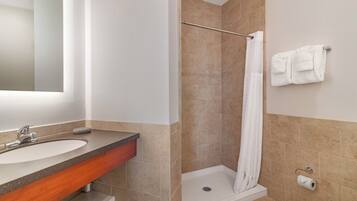 Une salle de bain équipée d’un lavabo, d’un miroir, d’une douche, de toilettes et d’un porte-serviettes.