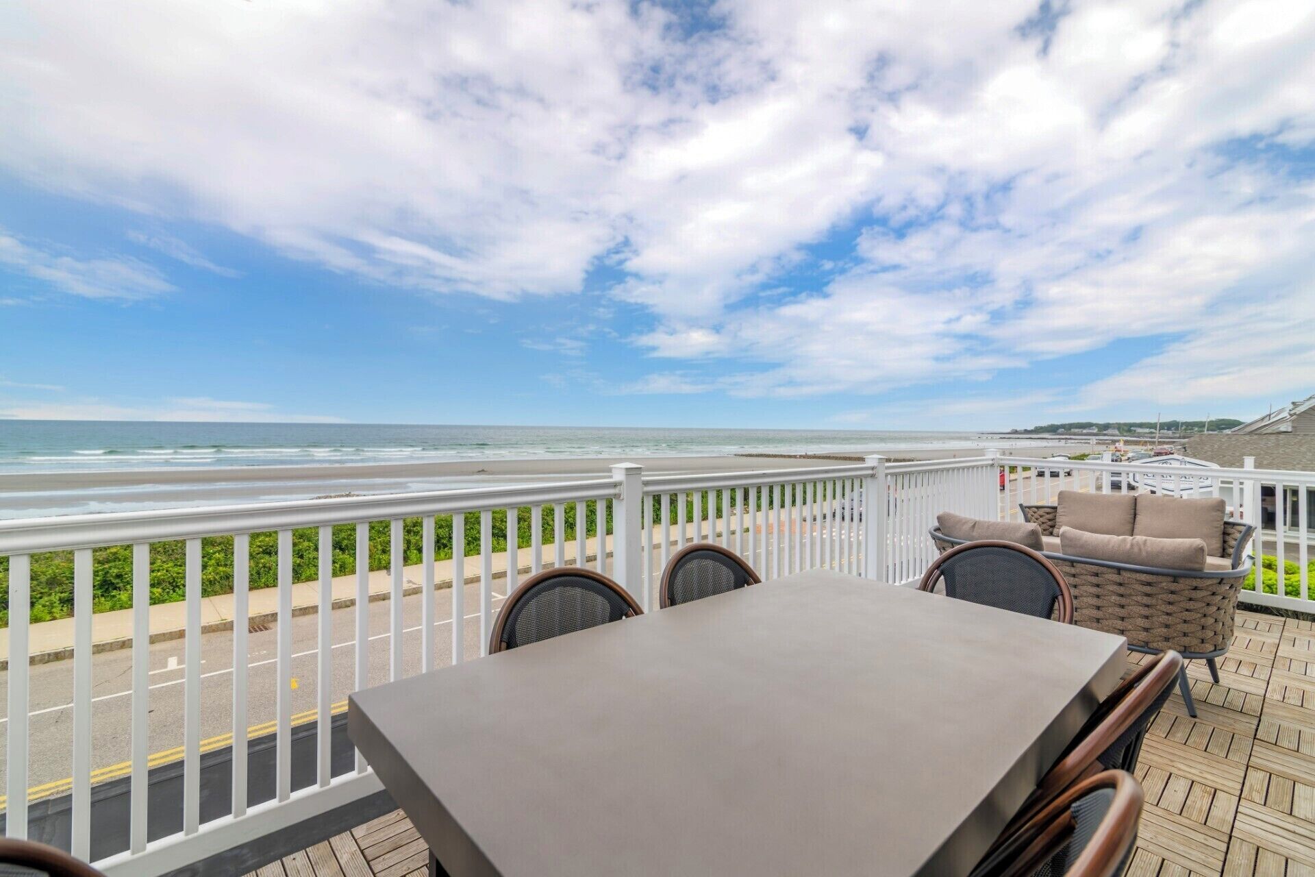 A deck with a table and chairs overlooking a beach.