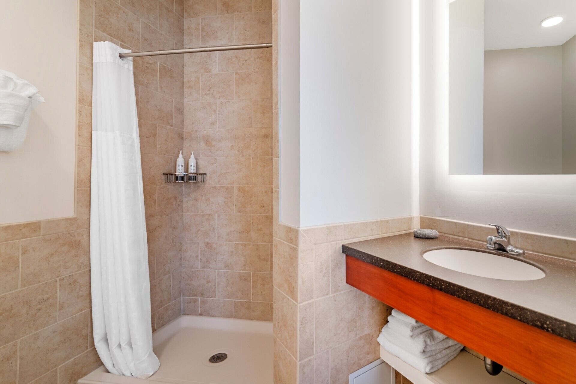 Ein Badezimmer mit Dusche, Waschbecken und Spiegel.