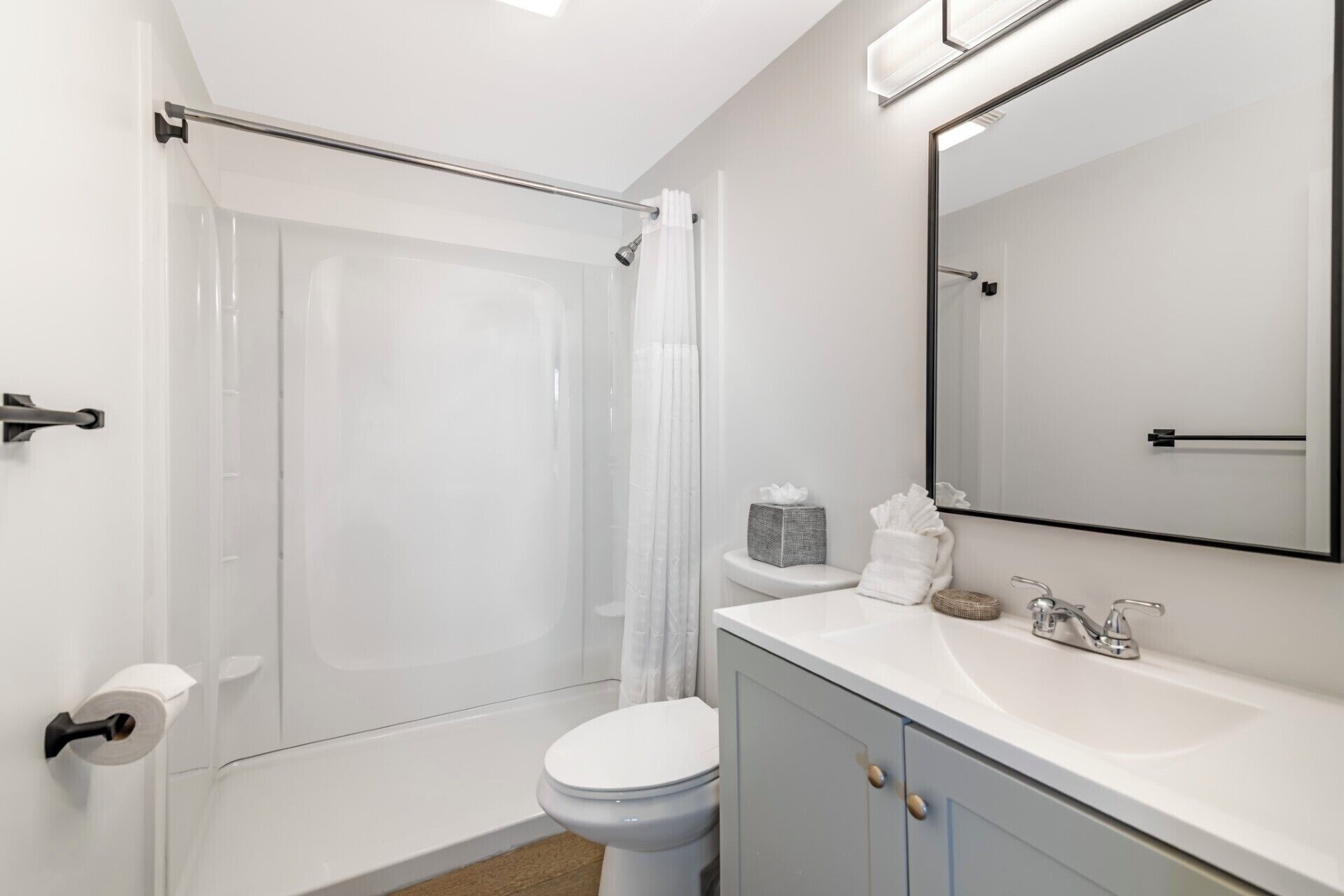 A bathroom with a shower, toilet, sink, and mirror.