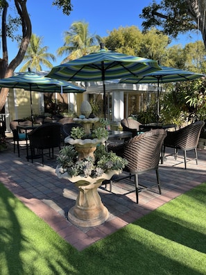 An outdoor patio with wicker furniture, stone planters, and striped umbrellas. - Bay Harbor Lodge (Key Largo)