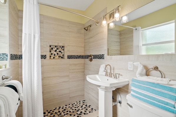 A bathroom with a shower, sink, and a mirror.