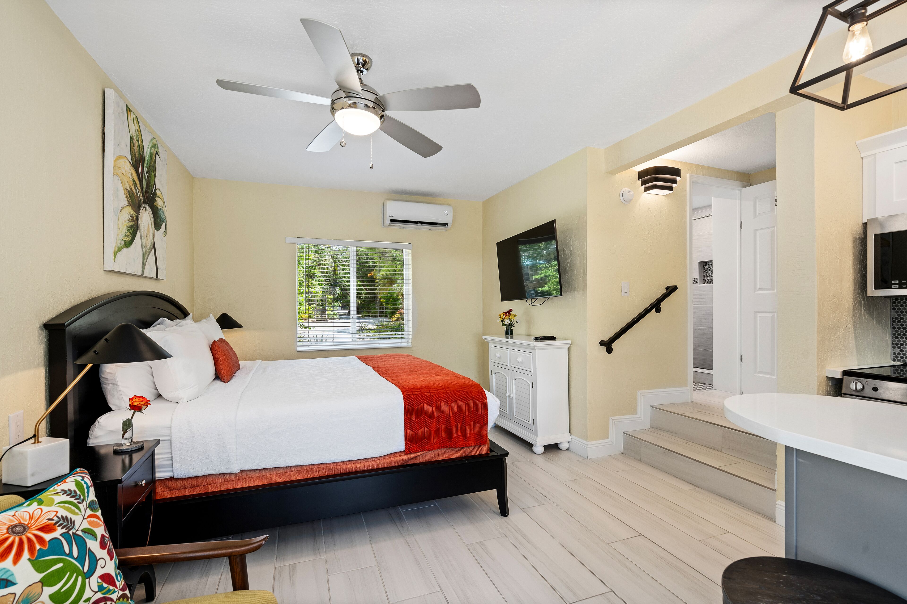 Camera da letto con un letto, comodino, lampada e ventilatore a soffitto.