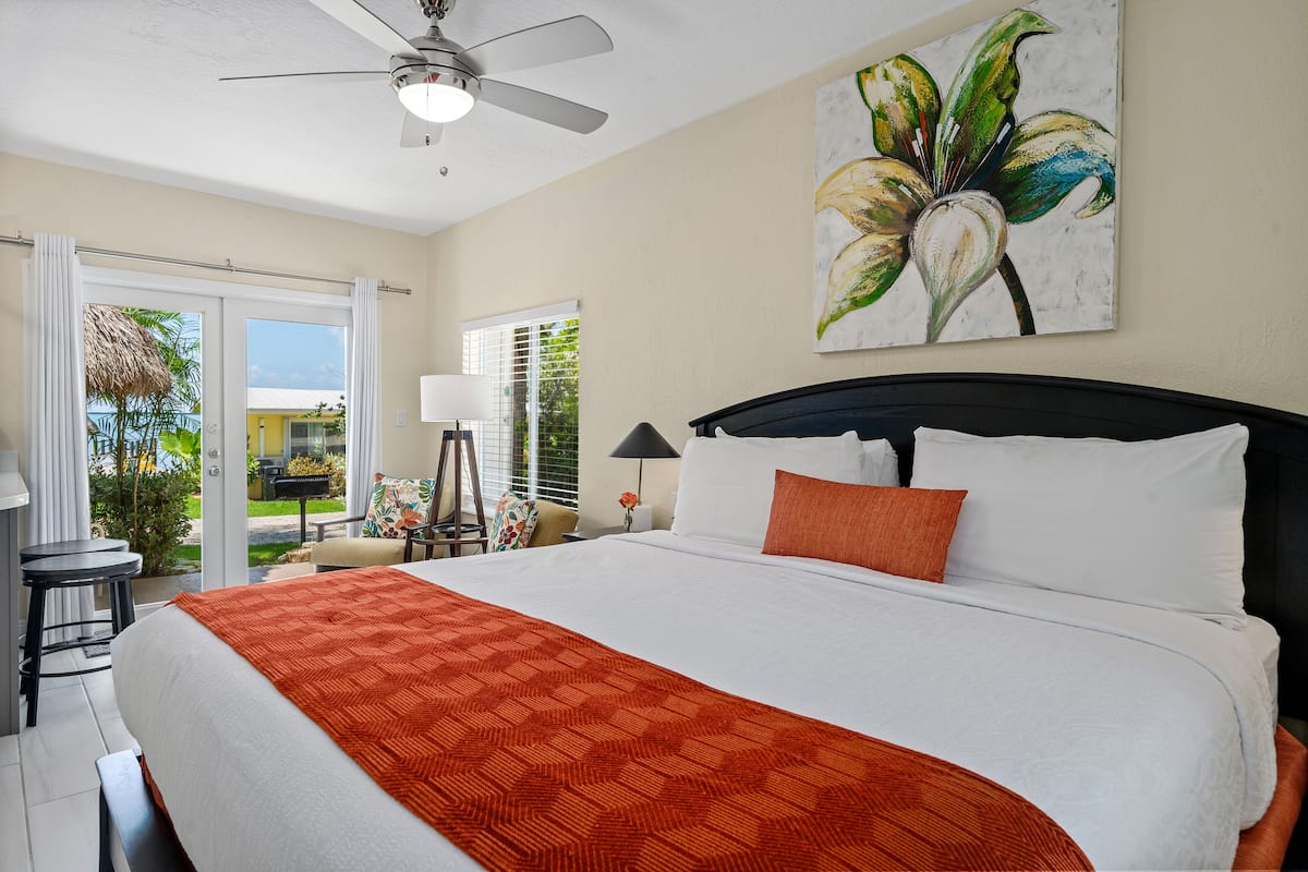 A spacious bedroom with a large bed, a ceiling fan, and a view of the outdoors.