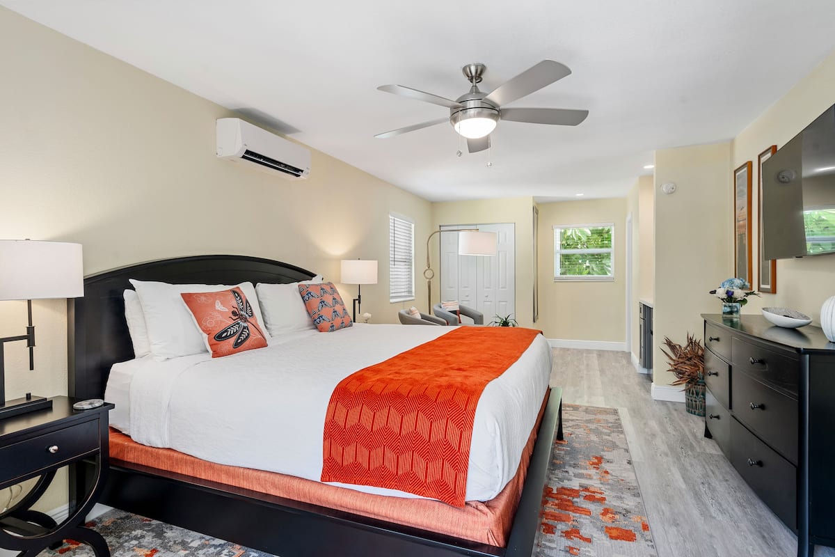 A bedroom with a bed, bedside tables, a ceiling fan, a dresser, and a mirror.