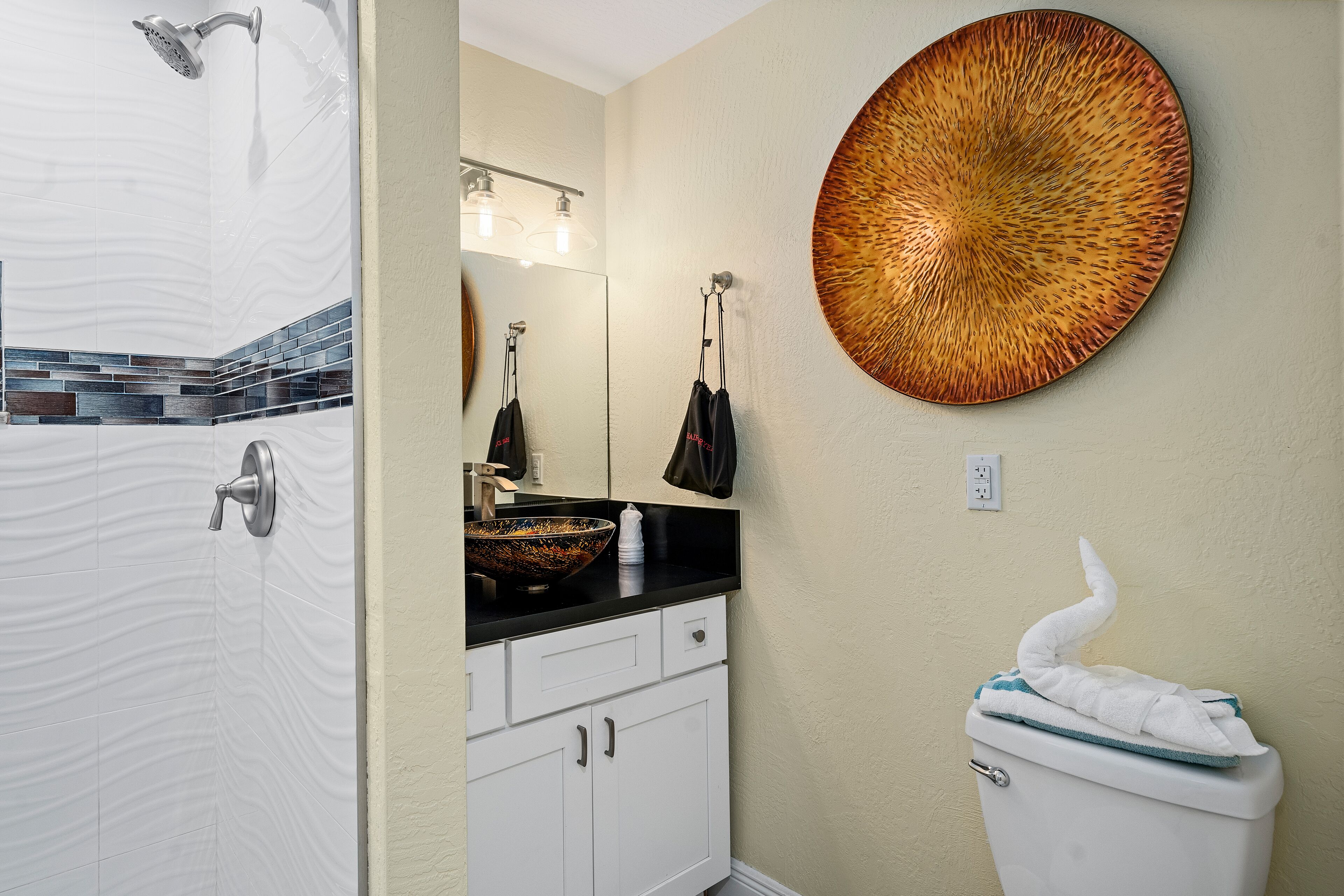 Een badkamer met een douche, een wastafel met een grote spiegel en een toilet.