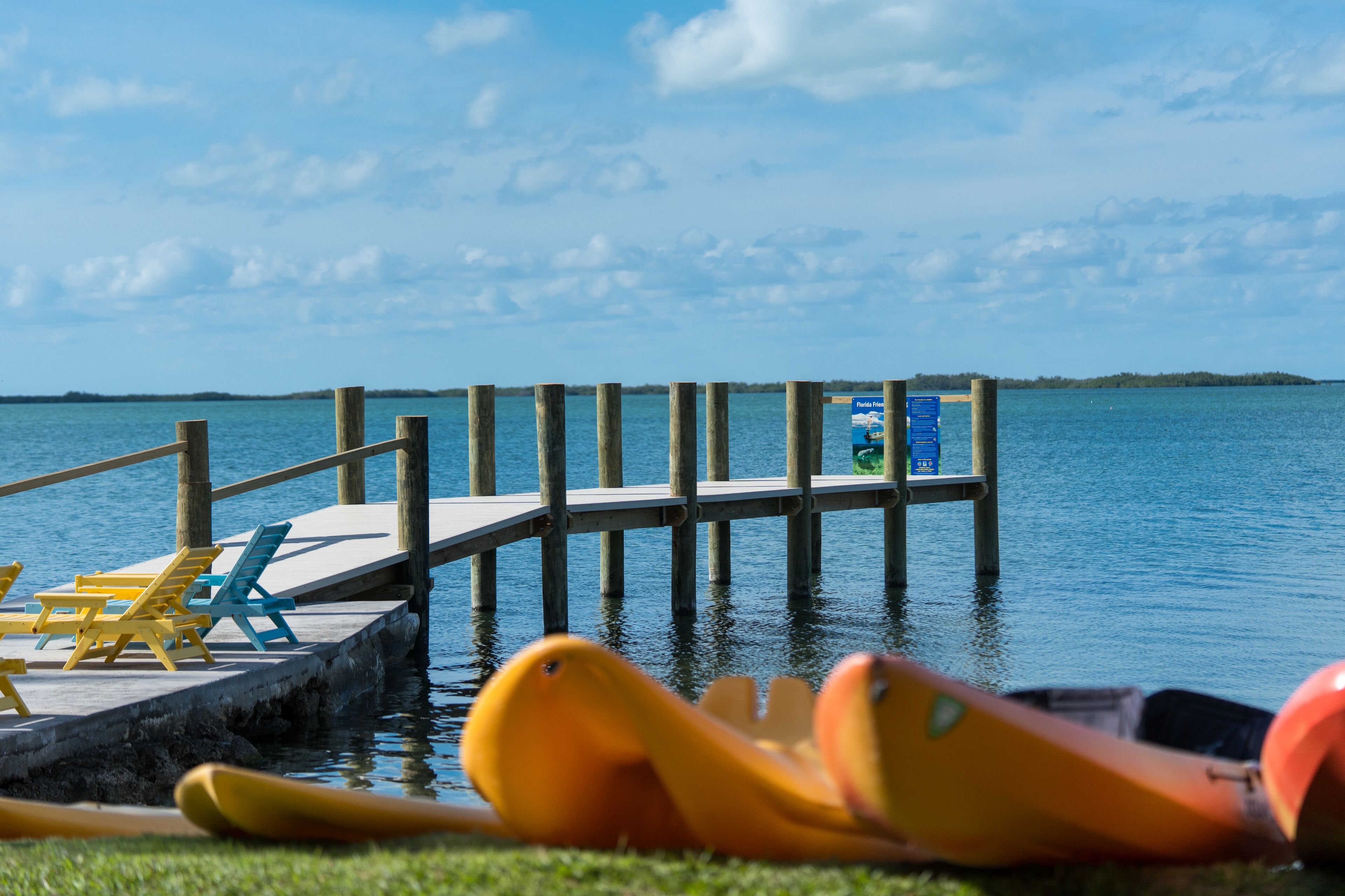 A wooden pier extending into calm water, with a small dock area featuring a table and chairs.