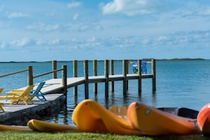 A wooden pier extending into calm water, with a small dock area featuring a table and chairs. - Bay Harbor Lodge (Key Largo)