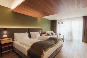 A hotel room with a large bed, a sofa, a desk, and a lamp.