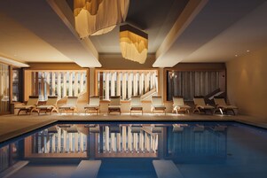 Area piscina interna moderna con sedie a sdraio e una scala.