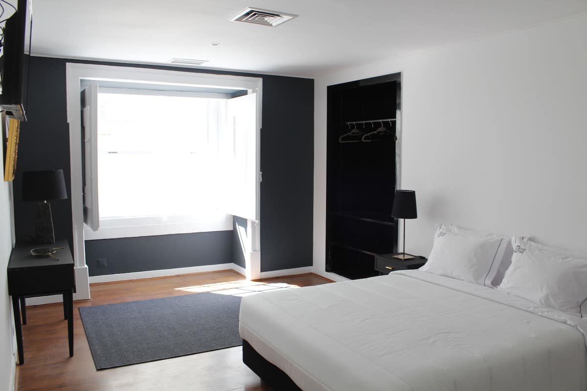 A bedroom with a bed, a wardrobe, a desk, and a chair.