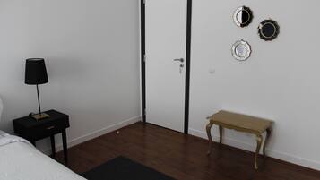 A bedroom with a bed, a bedside table with a lamp, a wooden bench, and a door.