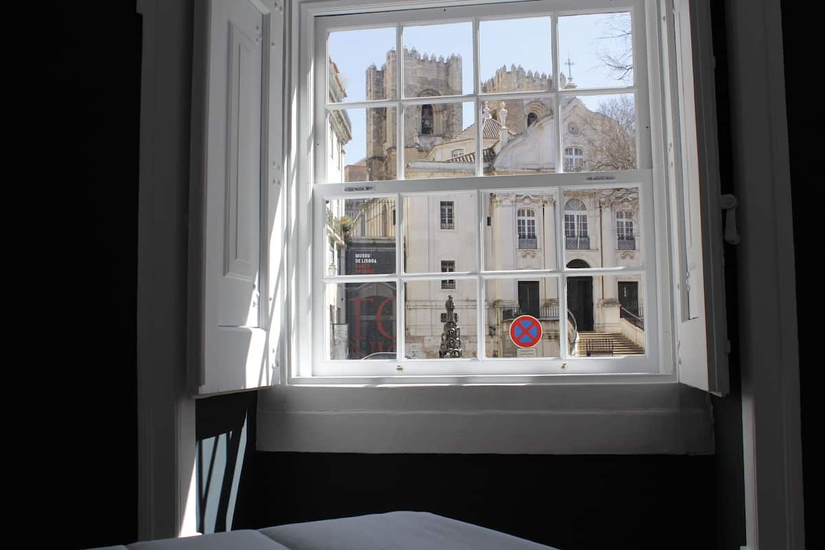 A window with a view of a historic building with multiple windows and a statue.
