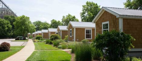 A row of single-story wooden cabins with metal roofs, a paved driveway, and well-maintained lawns.