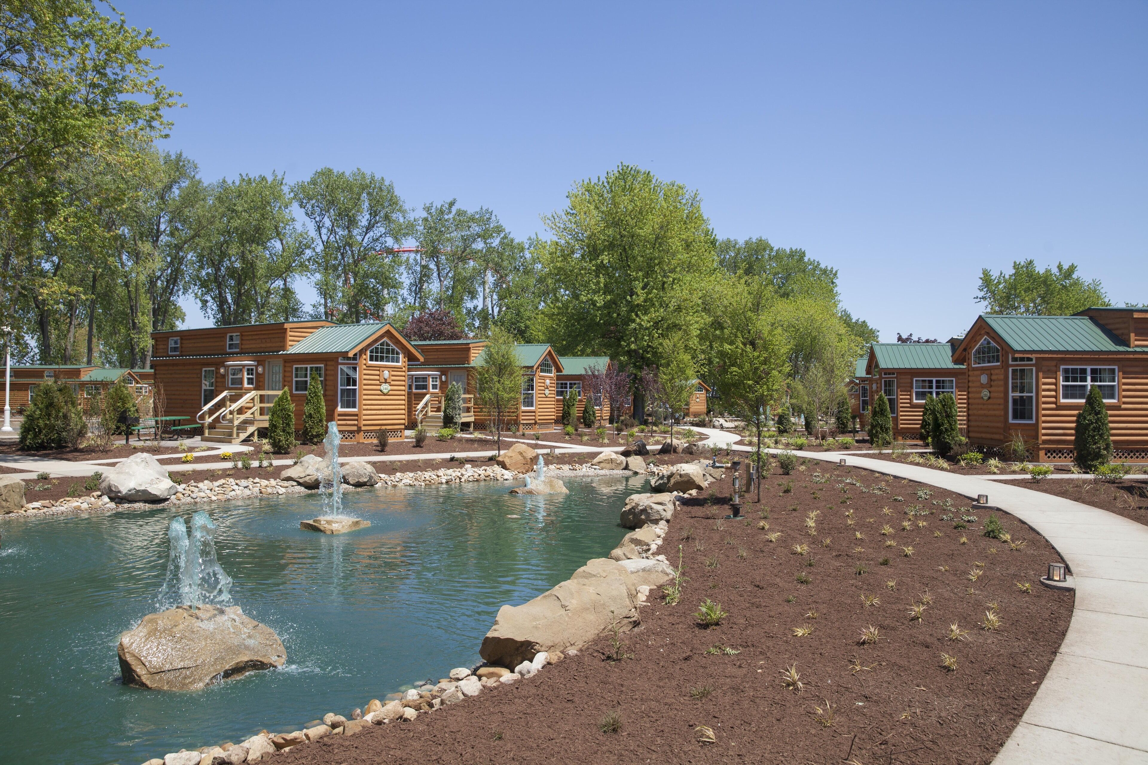 A lodge with a pond, wooden cabins, and a landscaped garden.