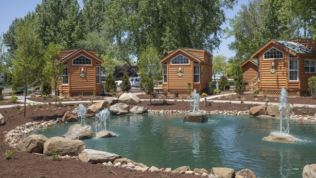 A log cabin-style hotel with a pond and fountain, surrounded by trees. - Cedar Point's Lighthouse Point (Sandusky)