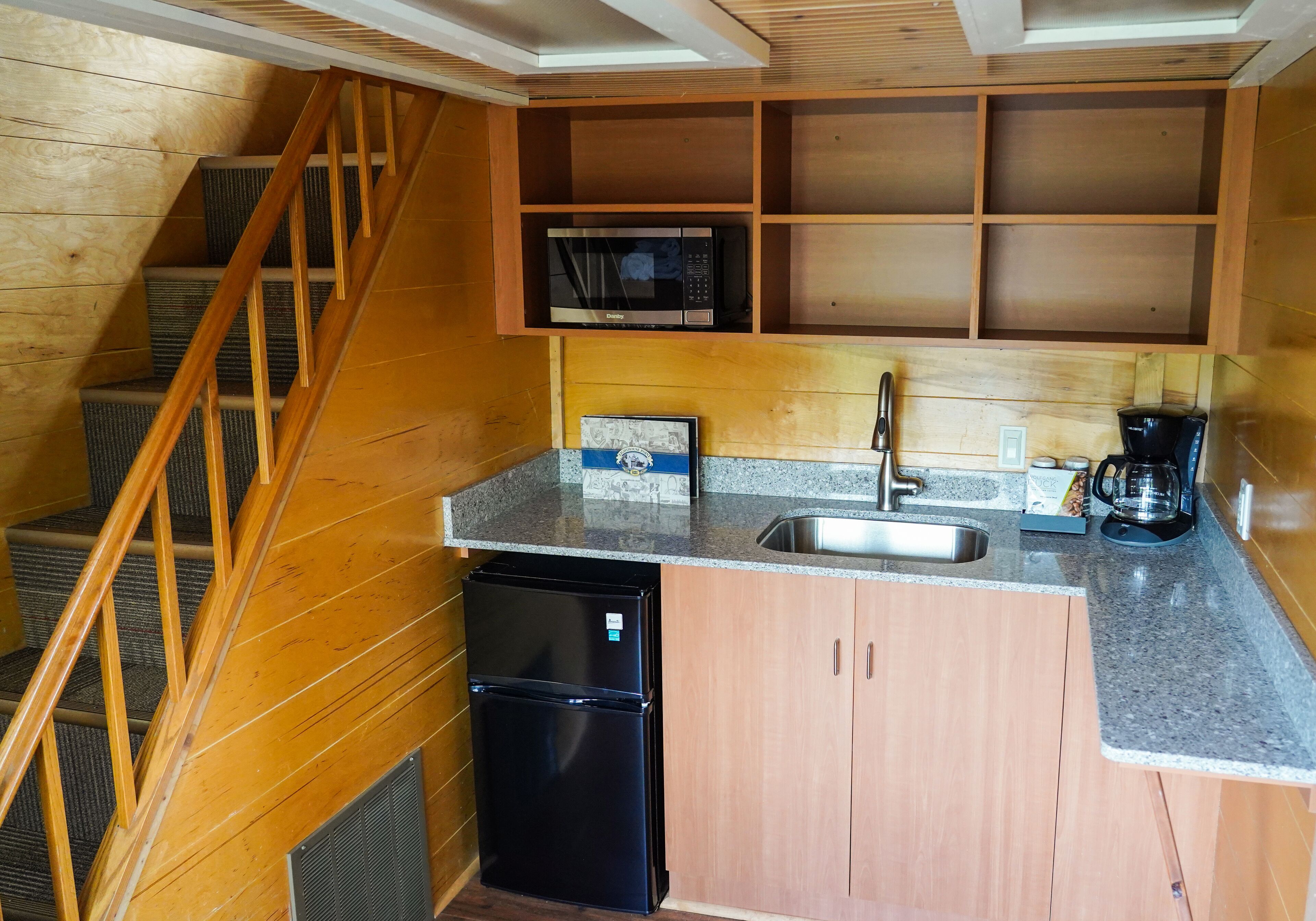 A compact kitchen with a built-in microwave, a coffee maker, and a refrigerator.