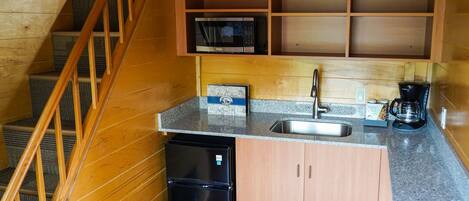 A compact kitchen with a built-in microwave, a coffee maker, and a refrigerator.