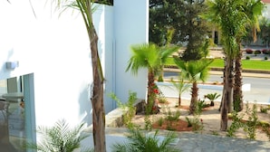 A modern building with a white facade, palm trees, and a stone pathway. - Ellia Hotel (Rhodes)