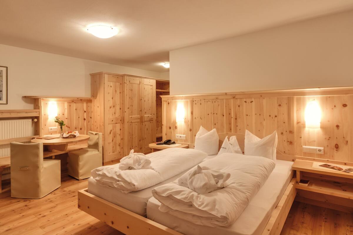 Une pièce aux murs lambrés, contenant un lit, un bureau et une chaise.