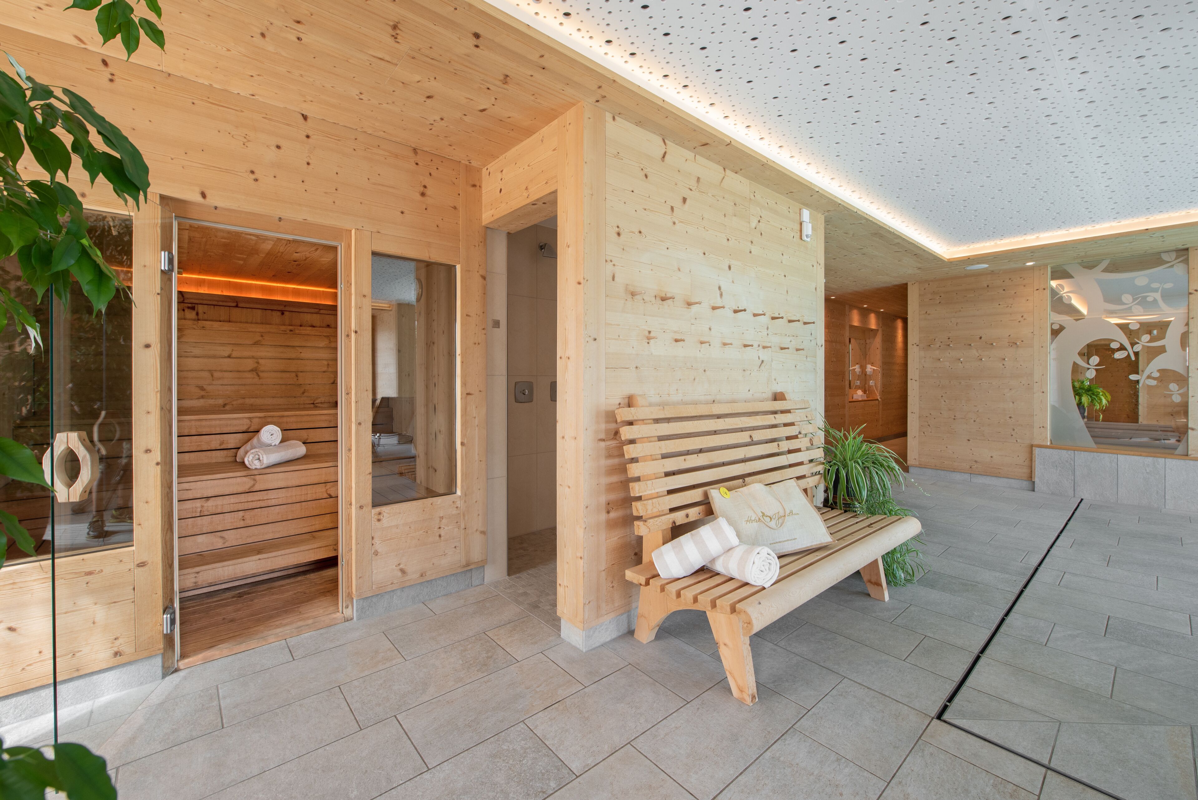 A wooden spa with a bench, a sauna, and a glass door.