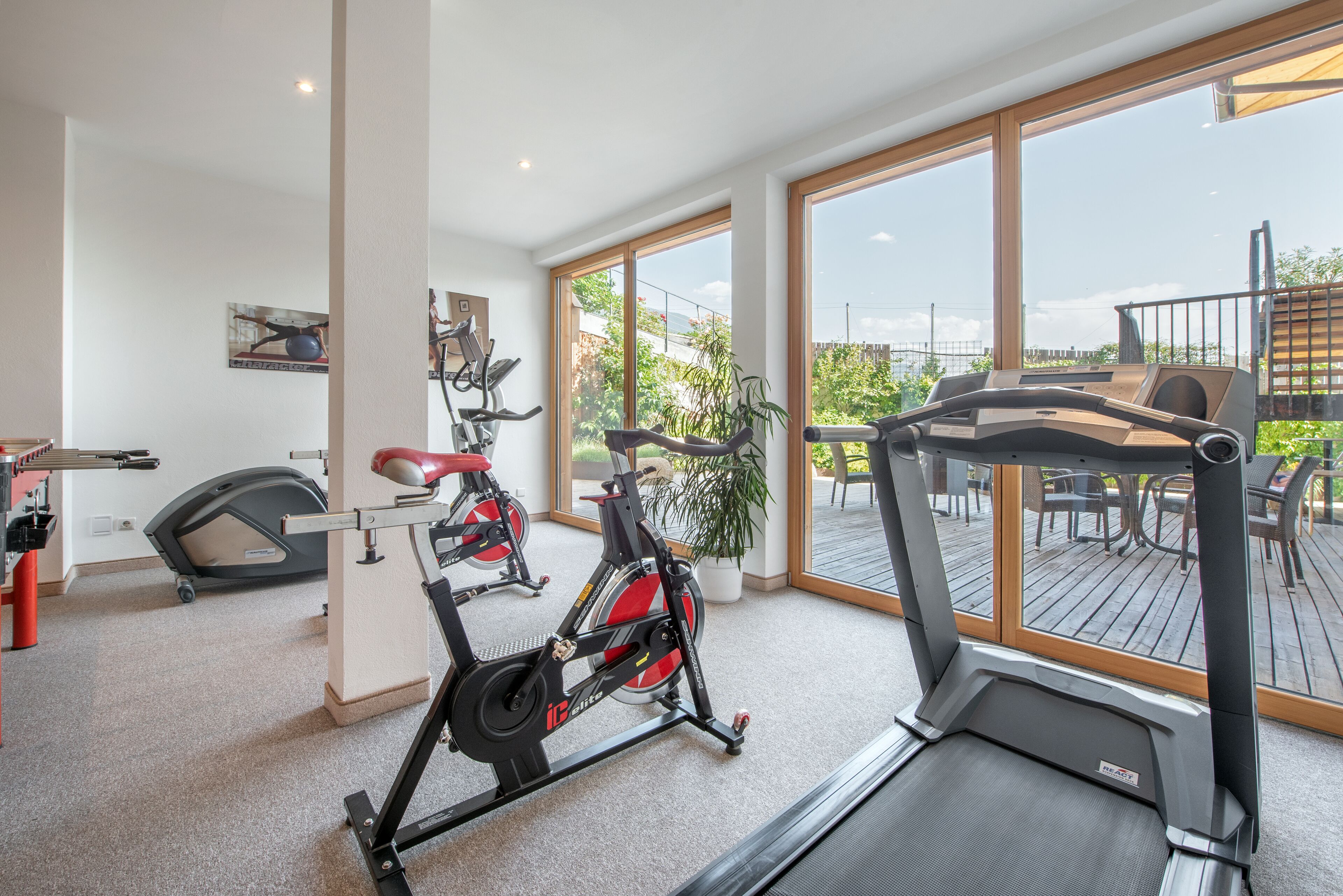 Ein Fitnessstudio mit Trainingsgeräten, großen Fenstern und Blick ins Freie.