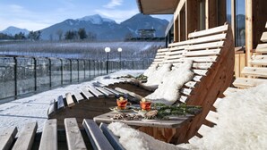 A wooden deck with benches and a table, overlooking a snowy landscape with mountains in the background. - Hotel Jonathan (Naz Sciaves)