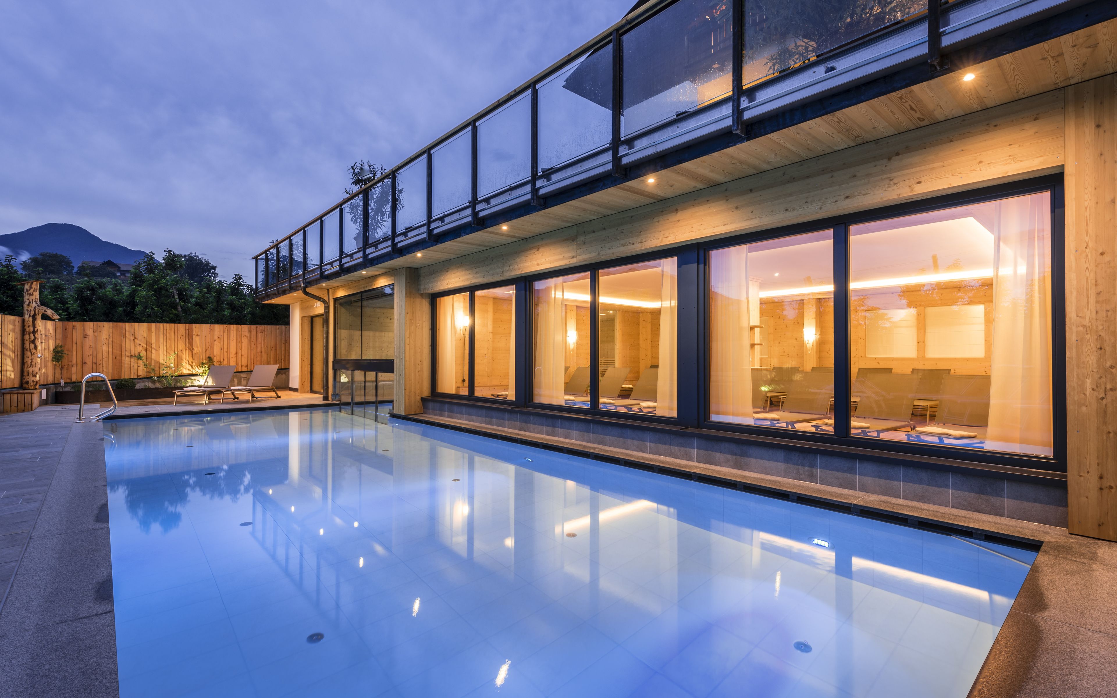 Una casa moderna con piscina, ventanas amplias y terraza de madera.