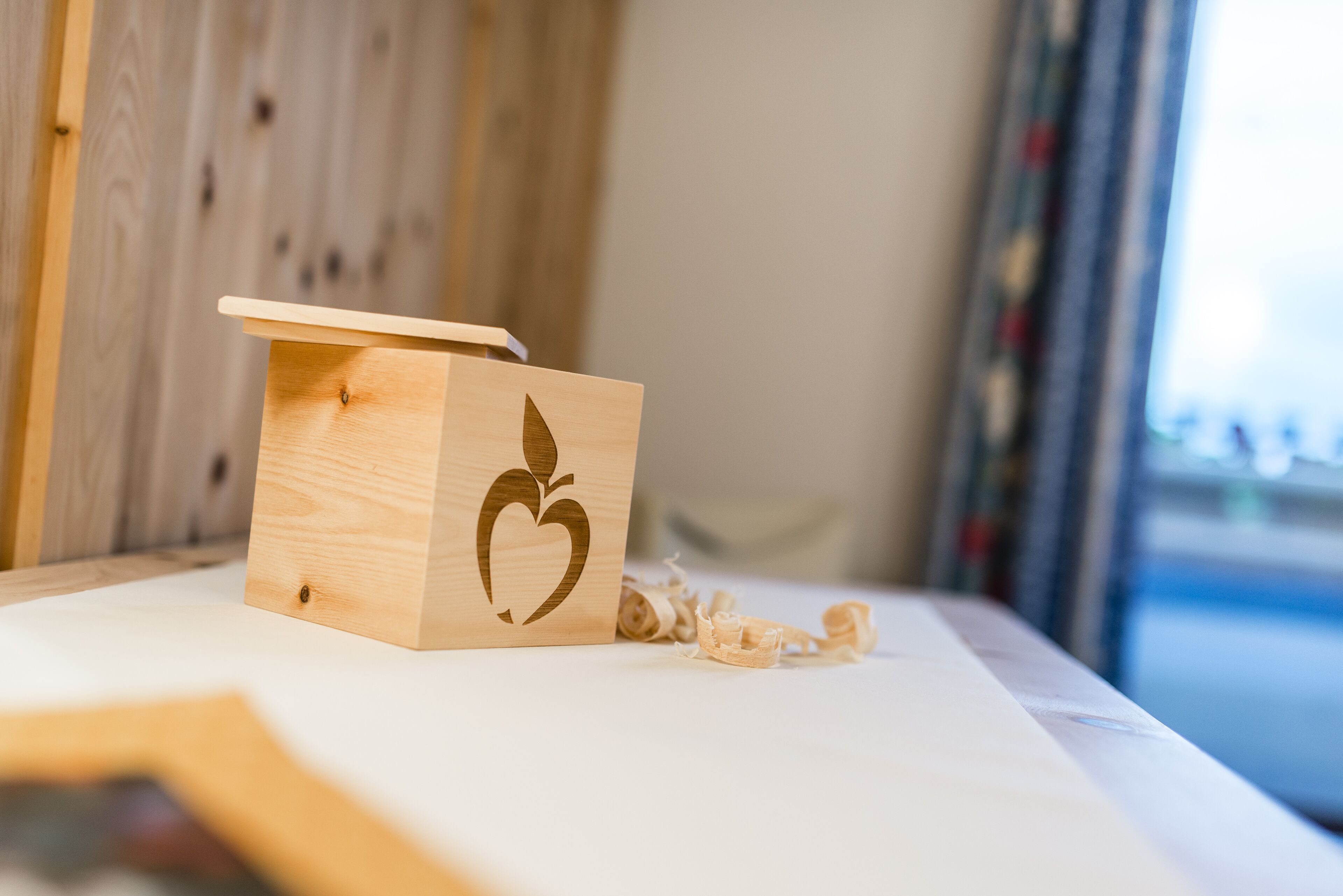 A small wooden box with a heart and leaf design on a table.