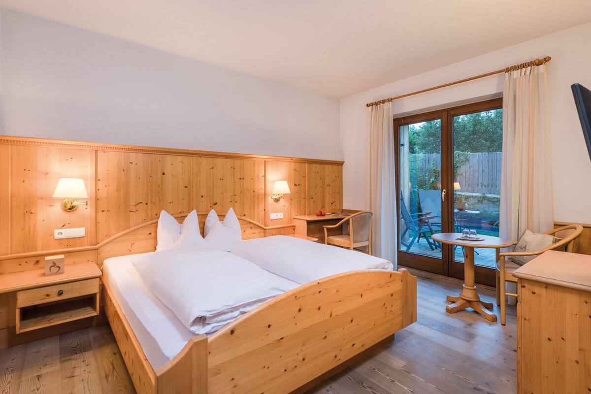 Une pièce en bois avec un lit, des tables de chevet, un bureau et une fenêtre avec des rideaux.
