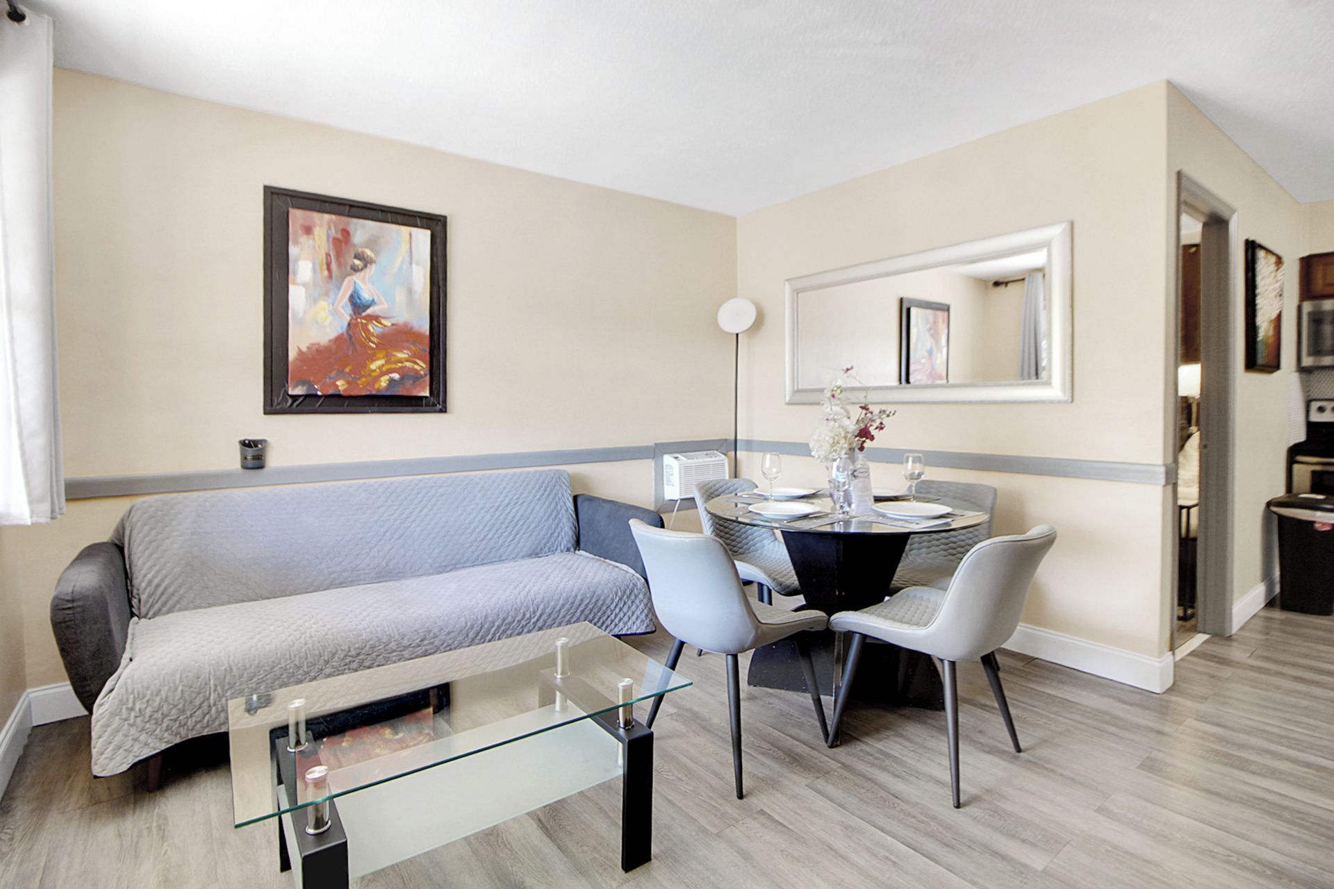 Un salon moderne comprenant un canapé, une table basse en verre et un coin repas avec des chaises et une table.