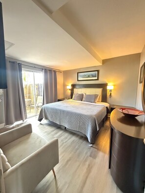 Une chambre d’hôtel avec un lit, un bureau, une chaise et une grande fenêtre avec des rideaux.