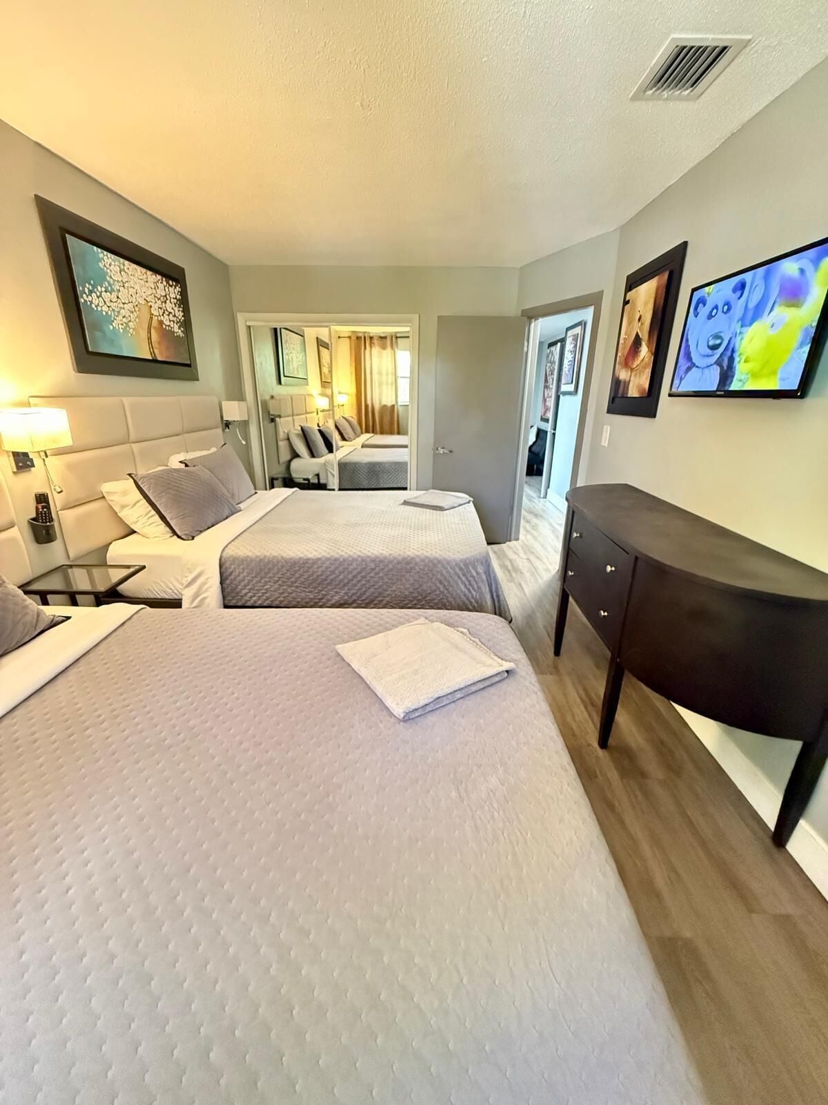 A hotel room with two beds, a desk, and a TV.