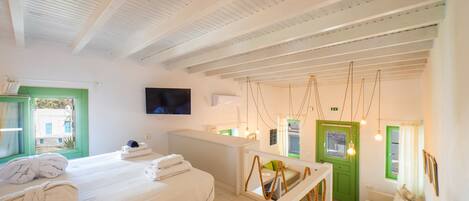 Habitación de hotel con una cama, una puerta verde, un escritorio blanco y un televisor en la pared.