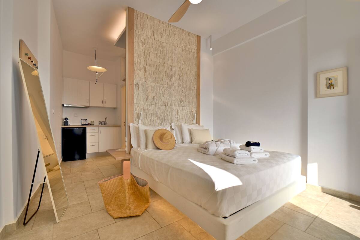 Une chambre moderne avec un grand lit, un petit coin cuisine et un plafond en bois.