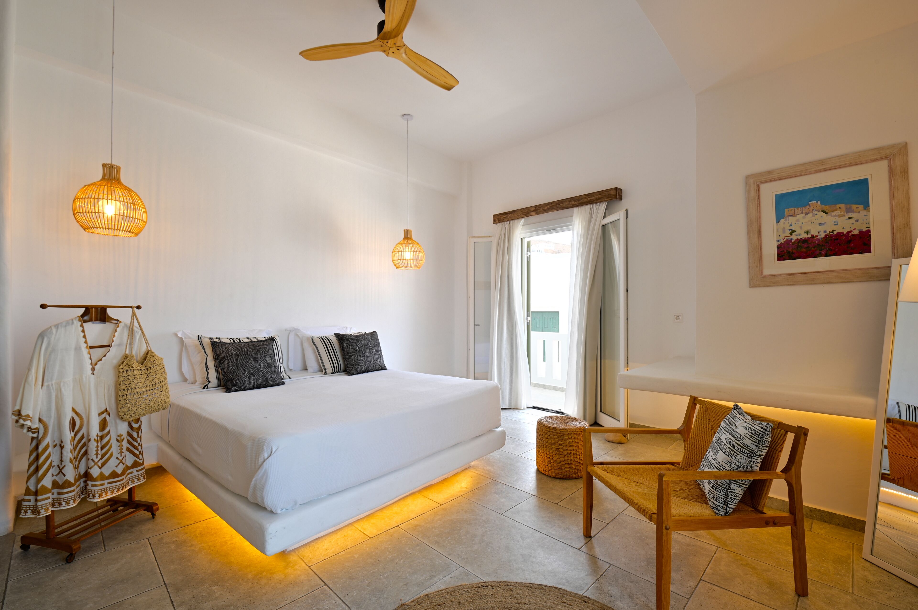 Ein Schlafzimmer mit einem Bett, einem Deckenventilator, einer Pendelleuchte, einem Sessel und einem Bild an der Wand.