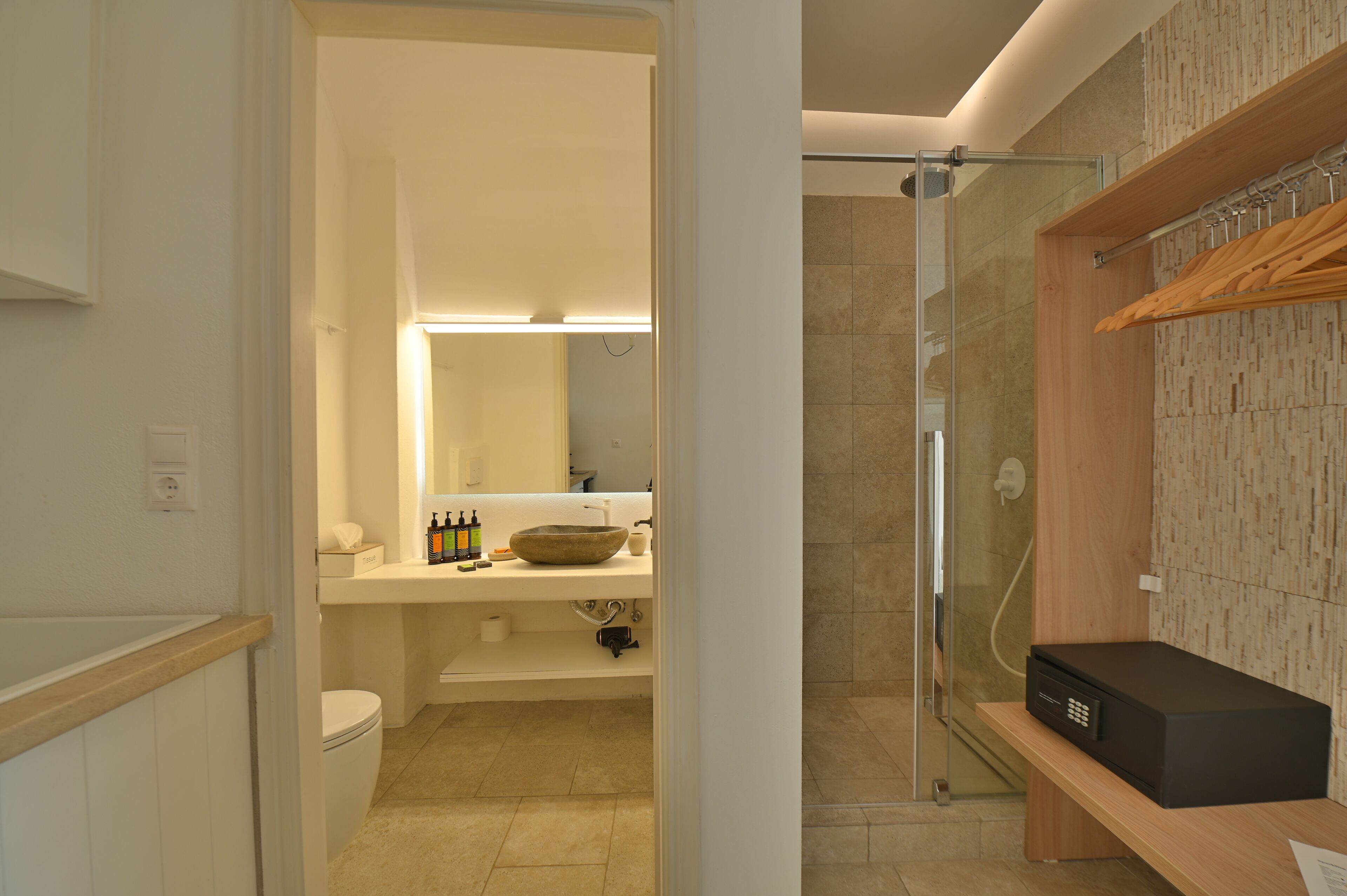 Un baño moderno con un espejo grande, un lavabo con un recipiente, un inodoro y una zona de ducha con puerta de cristal.