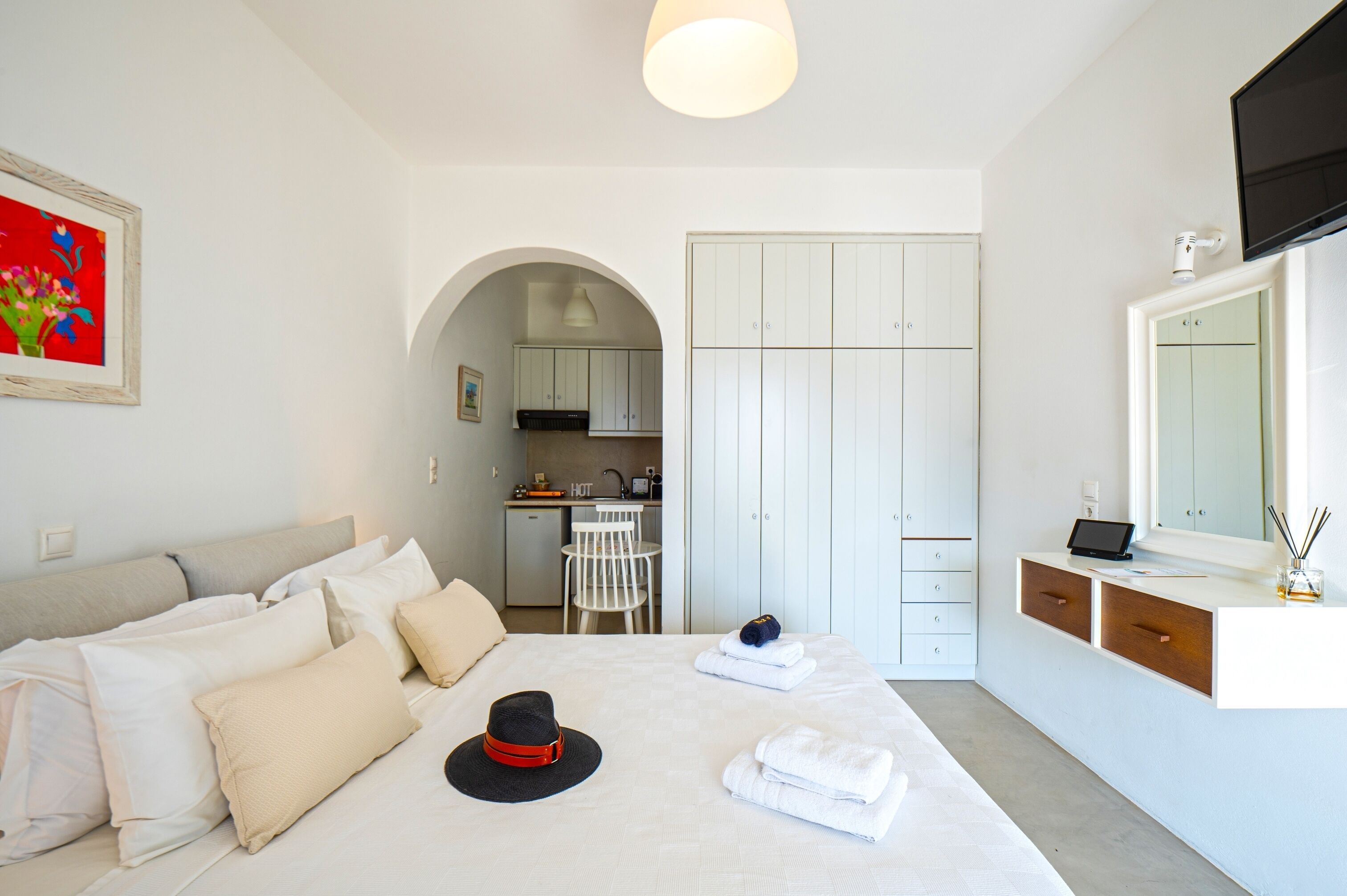 Una habitación de hotel con cama, escritorio, armario y kitchenette.