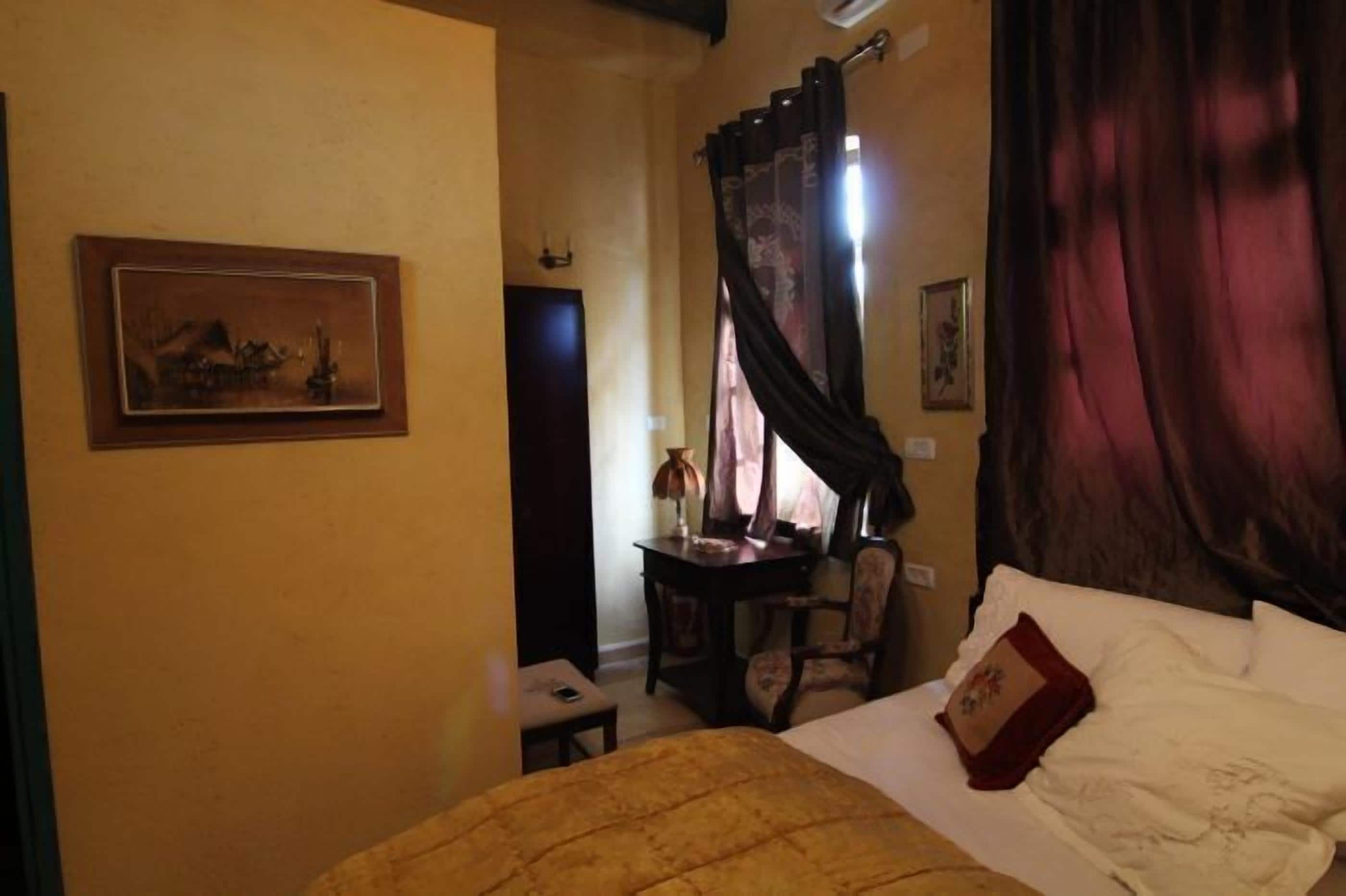 Een hotelkamer met een bed, een bureau, een stoel en een schilderij aan de muur.