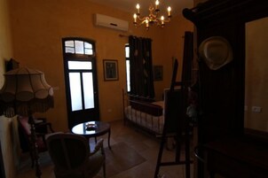 Una habitación con candelabro, una mesa, sillas, un sofá y una ventana con cortinas.