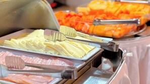 A buffet with various food items including sliced cheese, ham, and orange slices. - Hotel Portobelo beach (San Andrés)