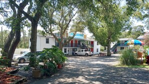 A campsite with RVs, a gravel path, and trees. - Captain's Cove Motel (Oak Island)