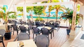 Enjoy a meal with a view of the ocean from our outdoor seating area, surrounded by palm trees and lush greenery.