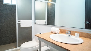 A modern bathroom with a white sink, a mirror, and a towel hanging on a rack.