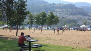 Una spiaggia con un campo da beach volley e un tavolo da picnic in primo piano.